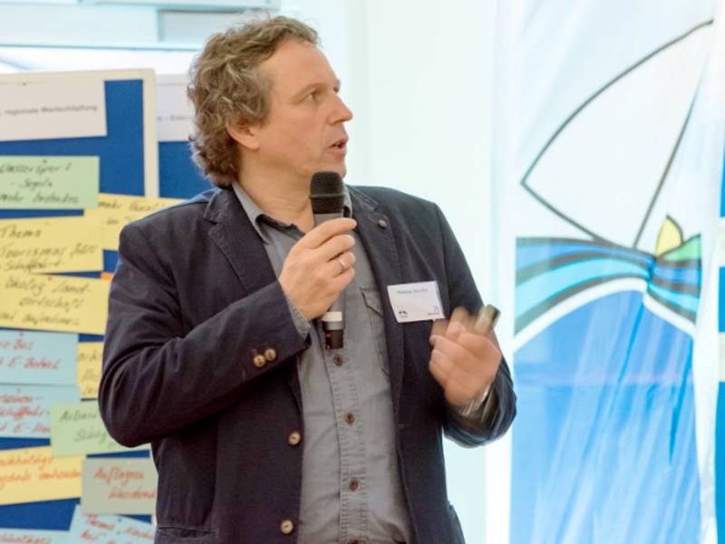 Ein Mann hält ein Mikrofon in seiner Hand und trägt vor.